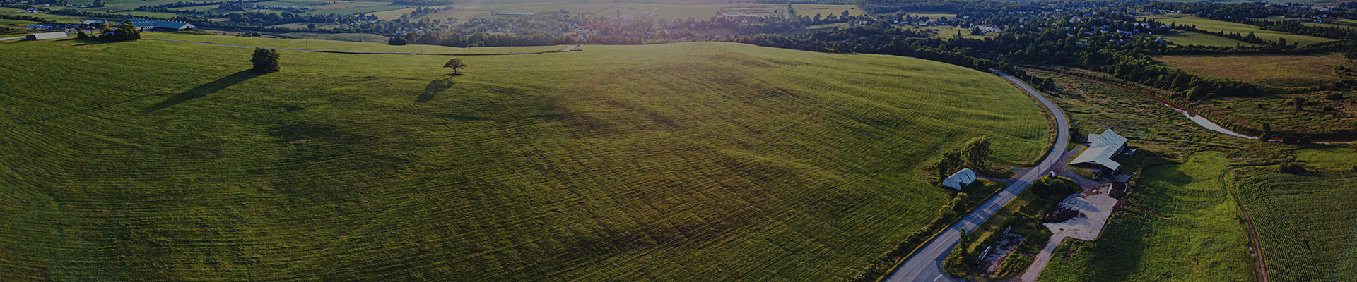 An aerial view of a rural landscape of grass & corn fields