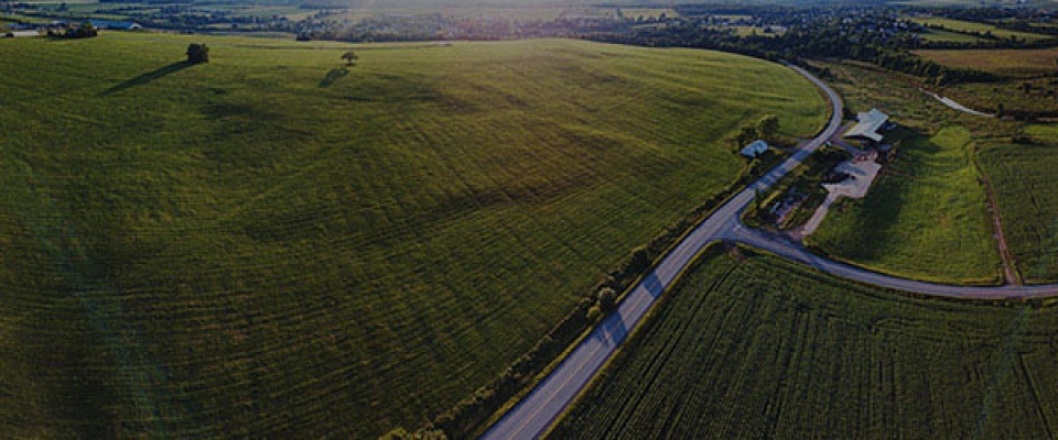 An aerial view of a rural landscape of grass & corn fields